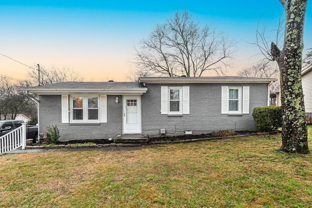 view of front of property featuring a lawn and brick siding