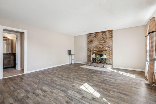 unfurnished living room featuring a textured ceiling, a fireplace, wood finished floors, and baseboards