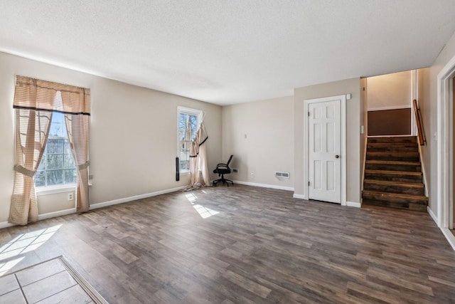 interior space featuring dark wood-style floors, a textured ceiling, baseboards, and stairs