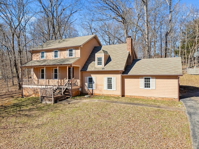 view of front facade featuring covered porch, a chimney, and a front yard