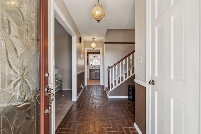 entrance foyer with stairs, brick floor, and baseboards