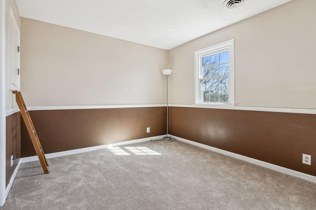 carpeted spare room with visible vents and baseboards