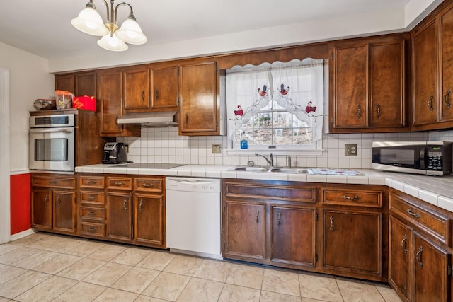 kitchen featuring tasteful backsplash, appliances with stainless steel finishes, light tile patterned flooring, a sink, and extractor fan