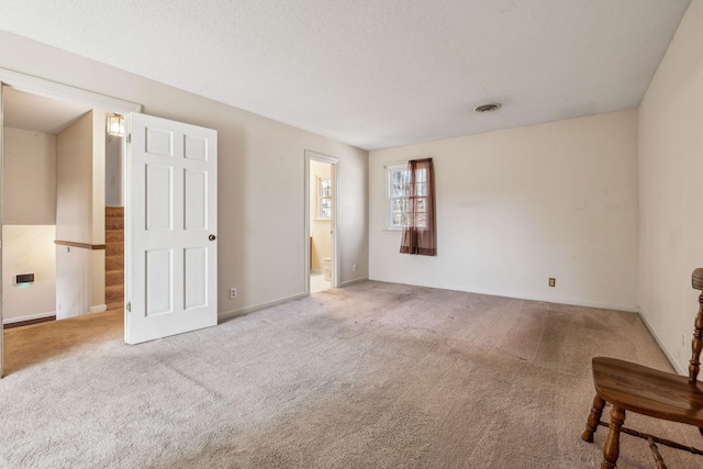 unfurnished room with a textured ceiling, carpet flooring, and visible vents