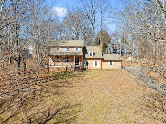 view of front facade featuring driveway, a chimney, and a front lawn