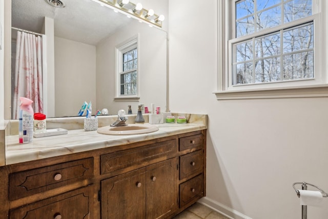 bathroom with a shower with shower curtain, tile patterned flooring, baseboards, and vanity