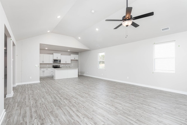 unfurnished living room with high vaulted ceiling, light wood-style flooring, visible vents, and baseboards