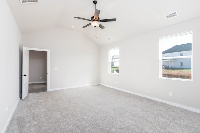 carpeted empty room featuring visible vents, vaulted ceiling, and baseboards