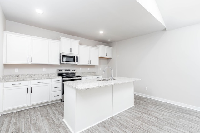 kitchen featuring light stone counters, appliances with stainless steel finishes, light wood-style floors, white cabinetry, and a sink