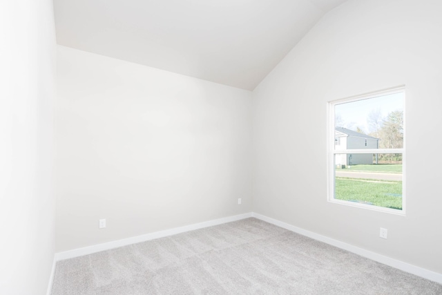 empty room featuring carpet, vaulted ceiling, and baseboards