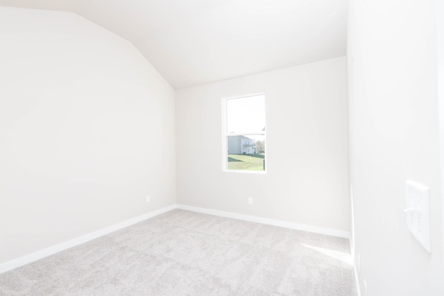 empty room with carpet floors, baseboards, and vaulted ceiling