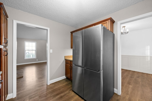 kitchen with dark wood-style floors, baseboards, a textured ceiling, and freestanding refrigerator