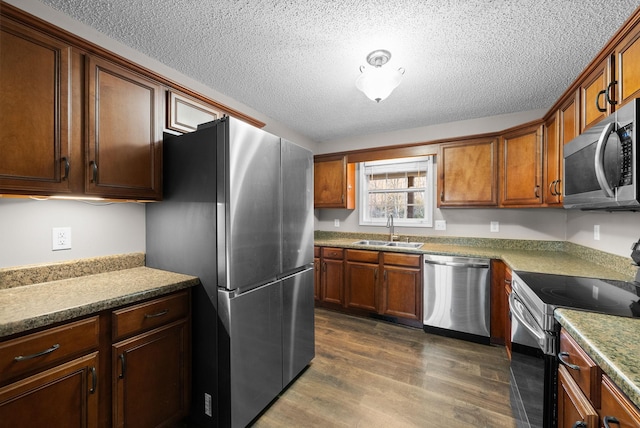 kitchen with a textured ceiling, appliances with stainless steel finishes, dark wood-type flooring, and a sink