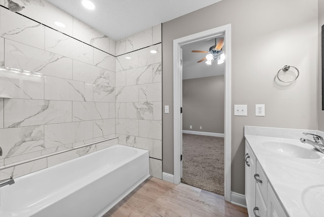 bathroom featuring double vanity, bathtub / shower combination, a sink, wood finished floors, and baseboards