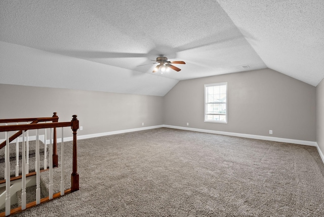 additional living space with baseboards, ceiling fan, vaulted ceiling, a textured ceiling, and carpet flooring