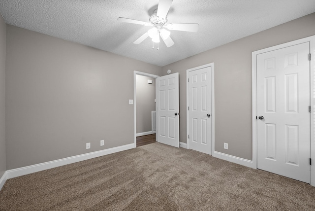 unfurnished bedroom with a textured ceiling, ceiling fan, carpet flooring, and baseboards