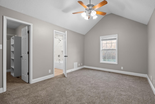 unfurnished bedroom with lofted ceiling, baseboards, a spacious closet, a closet, and carpet