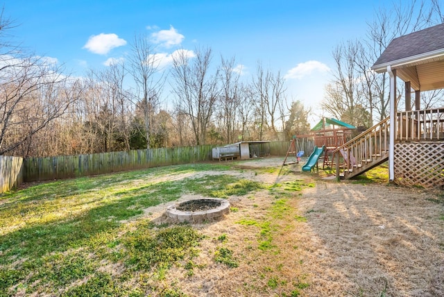 view of yard with an outdoor fire pit, a playground, and a fenced backyard