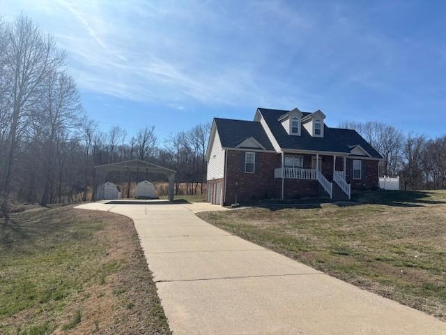 view of property exterior featuring a detached carport, covered porch, a lawn, and concrete driveway