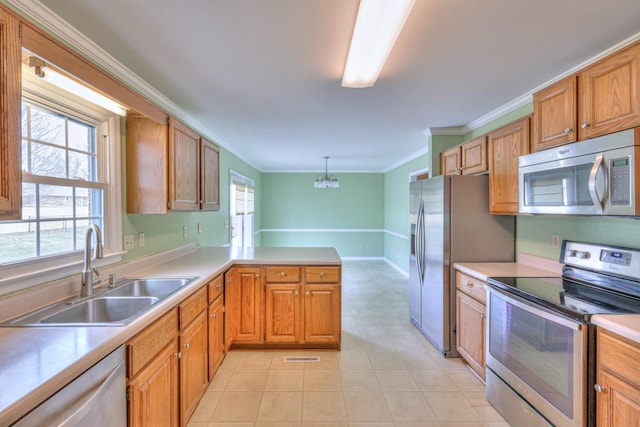 kitchen featuring light countertops, ornamental molding, appliances with stainless steel finishes, a peninsula, and a sink