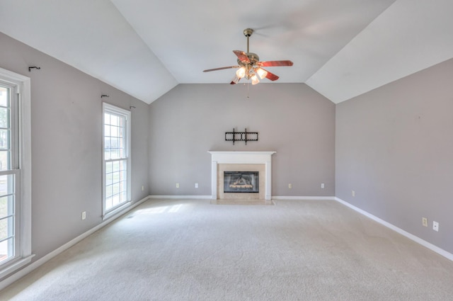 unfurnished living room with light carpet, ceiling fan, a fireplace with flush hearth, and vaulted ceiling