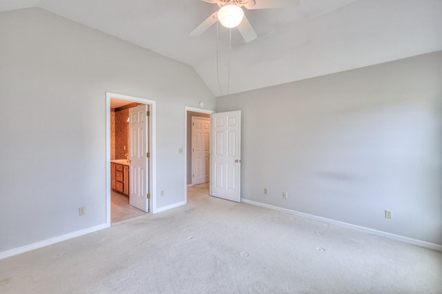 unfurnished bedroom with a ceiling fan, baseboards, lofted ceiling, ensuite bathroom, and light colored carpet