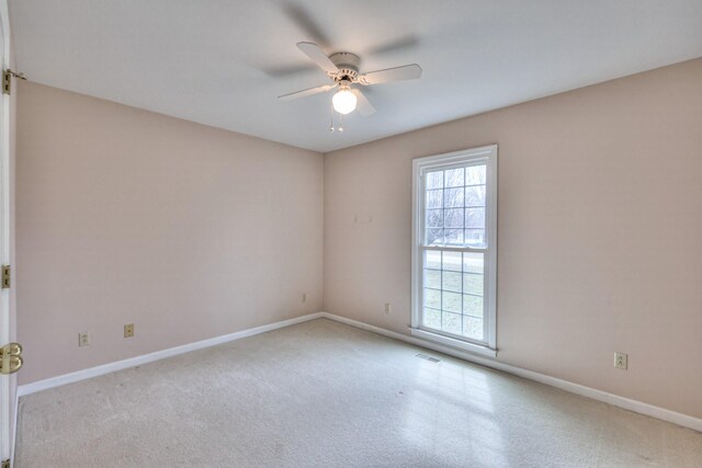 empty room with visible vents, a ceiling fan, and baseboards