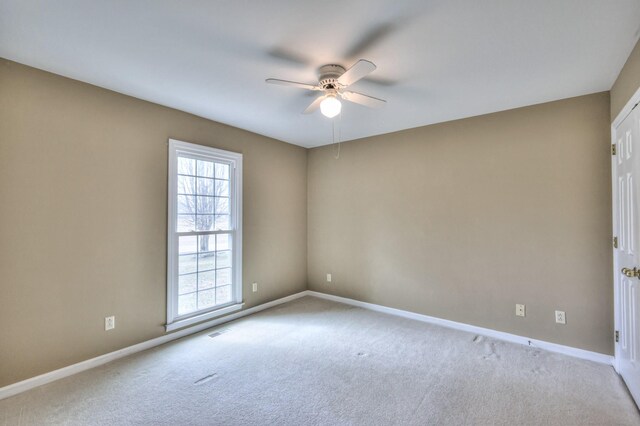 carpeted empty room featuring baseboards and a ceiling fan