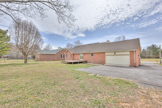 rear view of property with fence, driveway, an attached garage, a yard, and brick siding