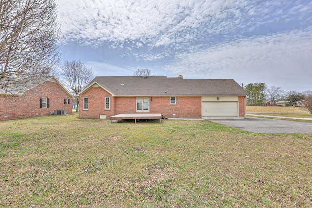 back of house with an attached garage, a yard, central AC, aphalt driveway, and brick siding