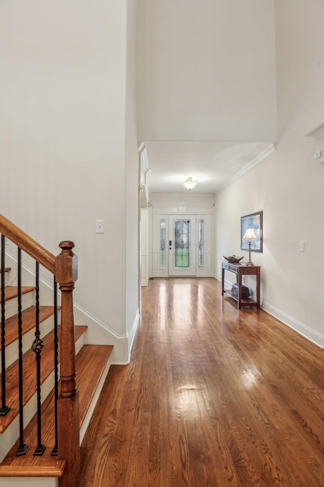 interior space with a towering ceiling, baseboards, wood finished floors, and stairs