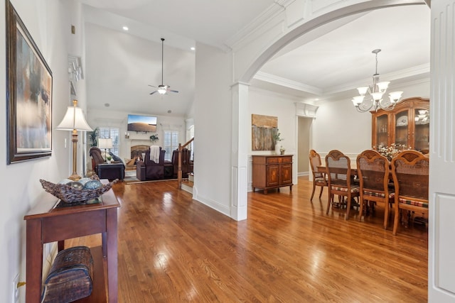 entryway with crown molding, light wood-style flooring, stairway, and arched walkways