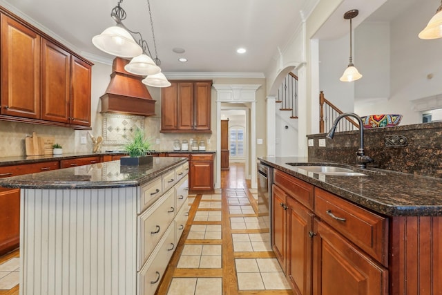 kitchen with custom exhaust hood, tasteful backsplash, a kitchen island with sink, and a sink