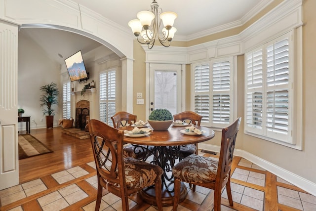 dining room featuring light tile patterned floors, baseboards, arched walkways, and crown molding