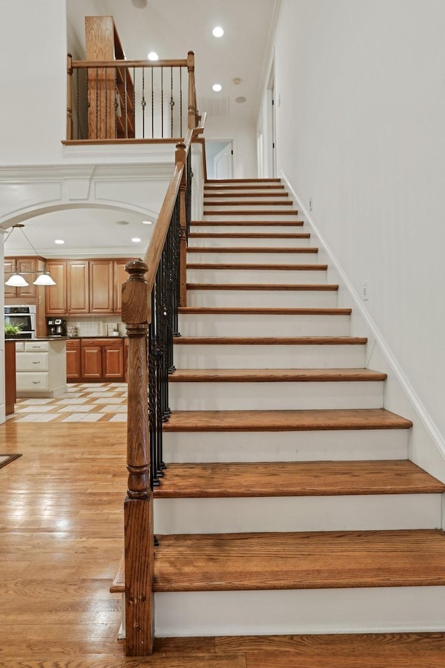 stairs featuring arched walkways, recessed lighting, and wood finished floors