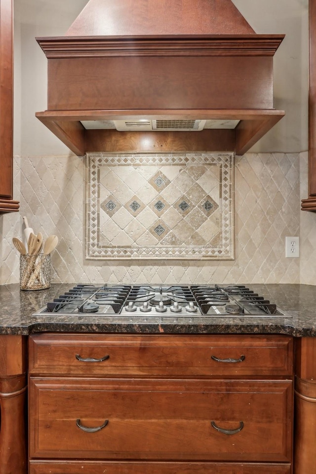 kitchen featuring premium range hood, dark stone counters, tasteful backsplash, and stainless steel gas cooktop