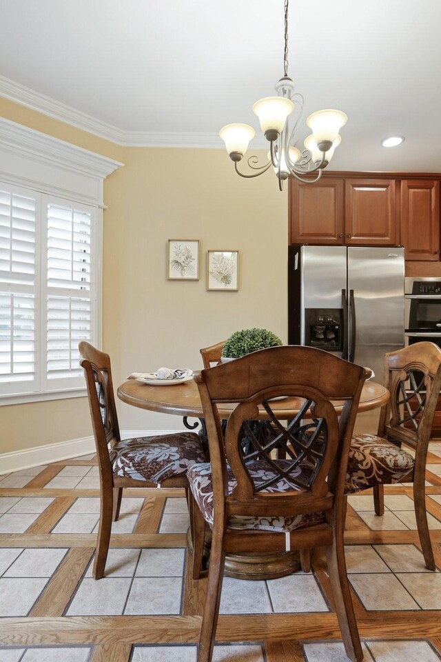 dining space with light tile patterned floors, a notable chandelier, baseboards, and ornamental molding