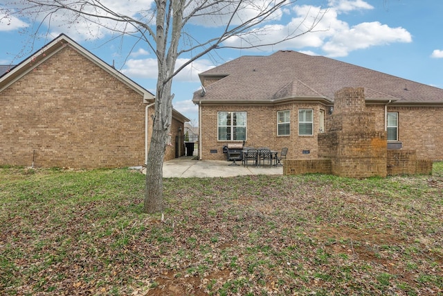 back of property featuring a yard, a shingled roof, crawl space, a patio area, and brick siding