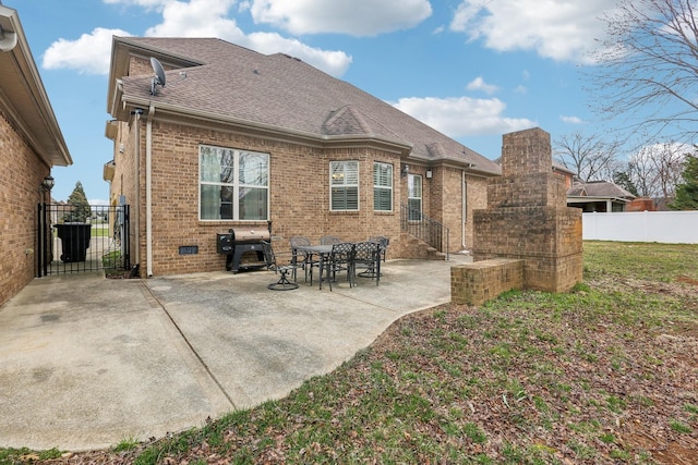 back of house featuring a patio, brick siding, a shingled roof, and fence