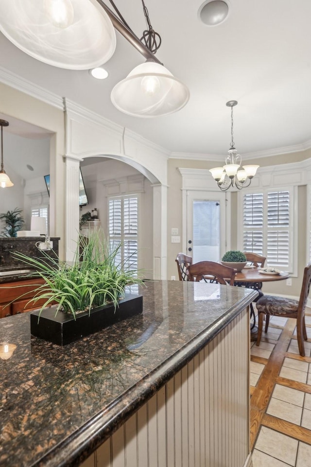 kitchen with decorative light fixtures, a notable chandelier, arched walkways, and ornamental molding