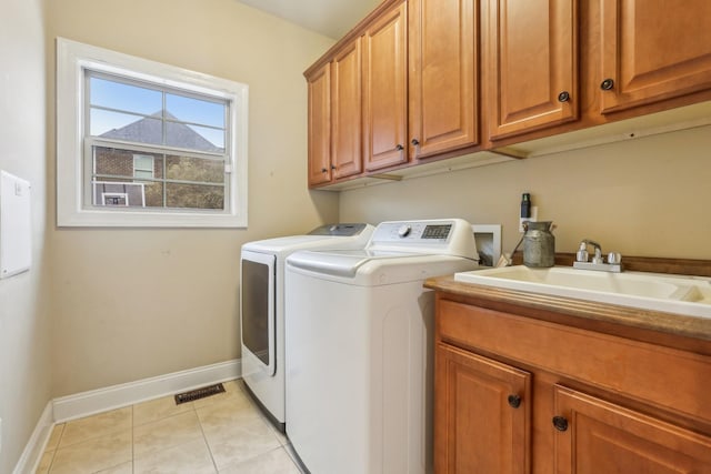 clothes washing area with washer and dryer, a sink, cabinet space, light tile patterned floors, and baseboards