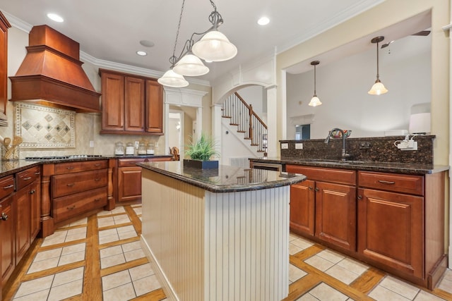 kitchen featuring a center island, arched walkways, crown molding, decorative backsplash, and custom exhaust hood