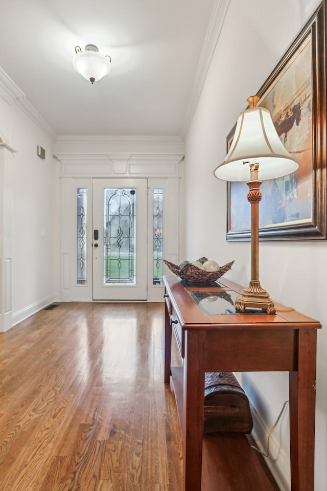 entrance foyer with crown molding, wood finished floors, and baseboards