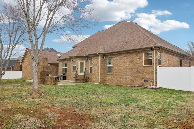 rear view of house with fence, a yard, crawl space, brick siding, and a patio area