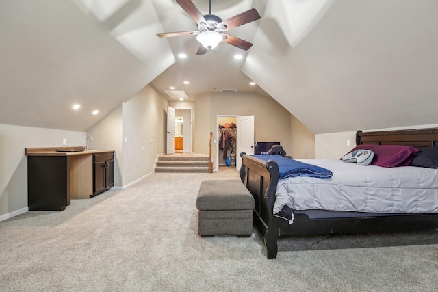 bedroom featuring light colored carpet, a walk in closet, baseboards, and vaulted ceiling