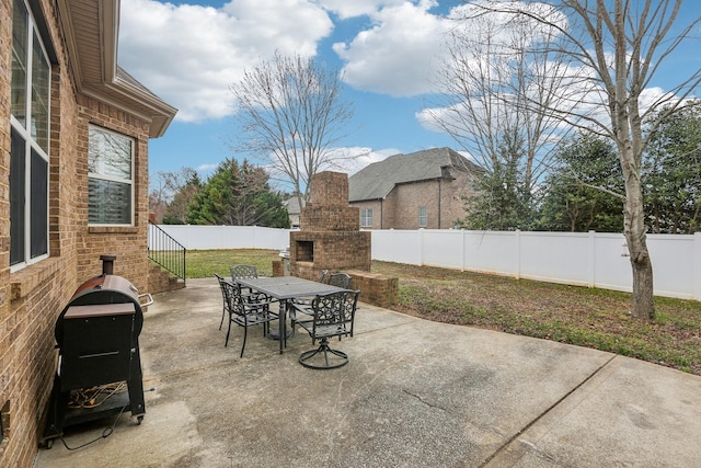 view of patio / terrace with a fenced backyard, outdoor dining area, and an outdoor brick fireplace