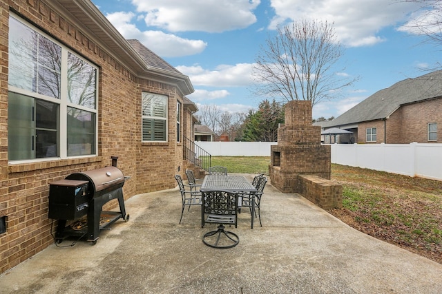 view of patio featuring area for grilling, outdoor dining area, a fireplace, and a fenced backyard