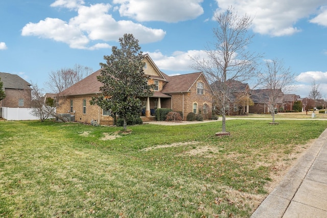 view of front of home with brick siding, a front lawn, and fence