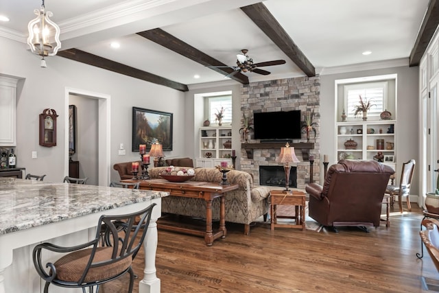 living area with a stone fireplace, dark wood-type flooring, a ceiling fan, beam ceiling, and crown molding