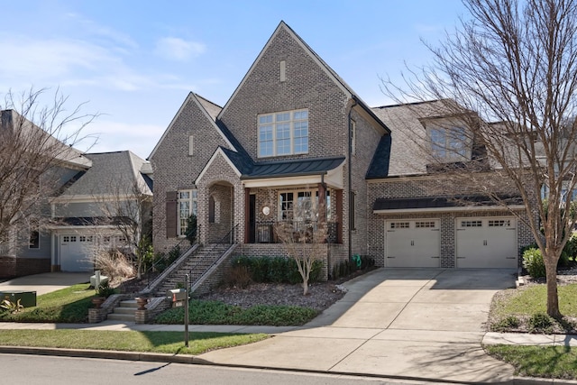 view of front of house featuring an attached garage, brick siding, stairs, concrete driveway, and a standing seam roof